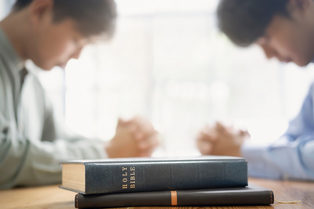 Two christian people are praying together over holy bible.